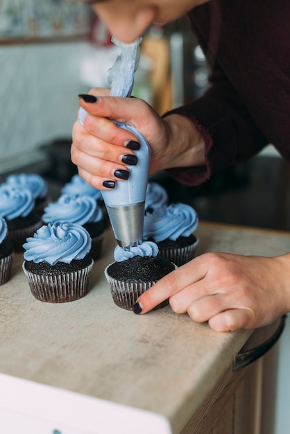 Crop woman decorating muffins