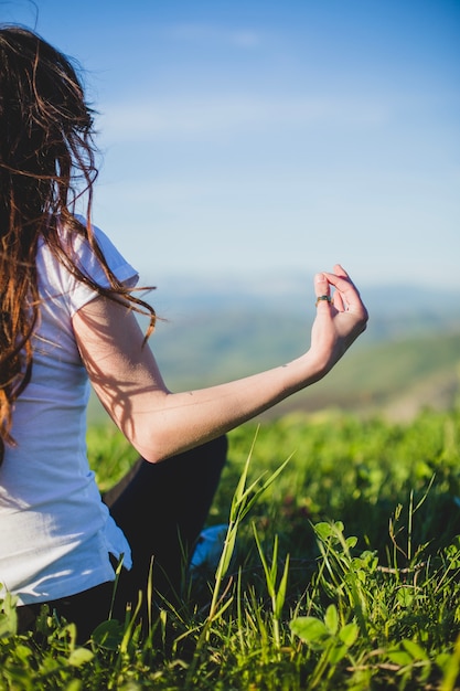 Free photo crop woman doing yoga on field