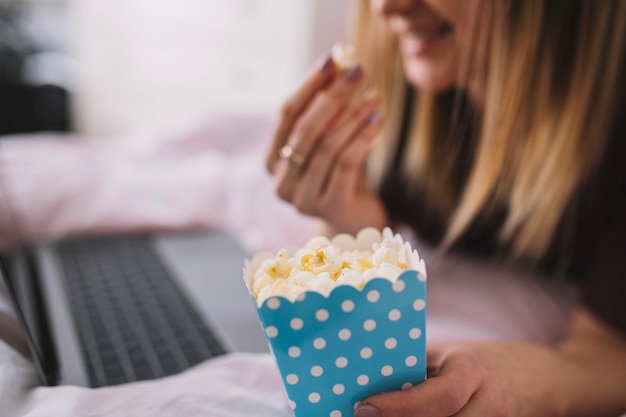 Free Photo crop woman eating popcorn while watching film