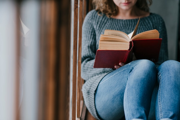 Free photo crop woman enjoying reading near window