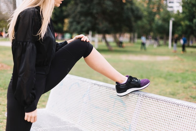 Crop woman exercising near bench