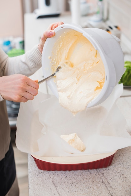 Free photo crop woman filling baking pan with batter