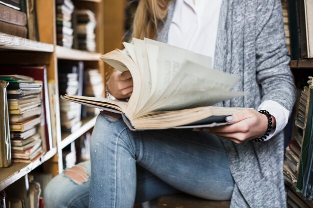 Crop woman flipping book pages