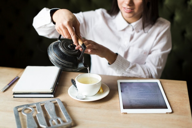 Free photo crop woman having tea while studying