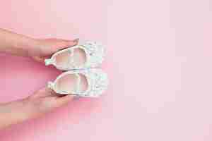 Free photo crop woman holding baby shoes