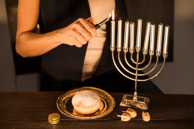 Crop woman lighting candles on menorah