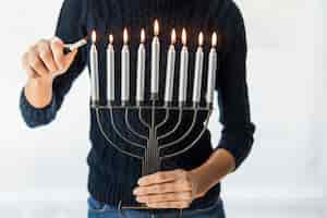 Free photo crop woman lighting candles on metal menorah