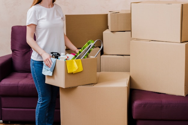 Free photo crop woman packing things near sofa