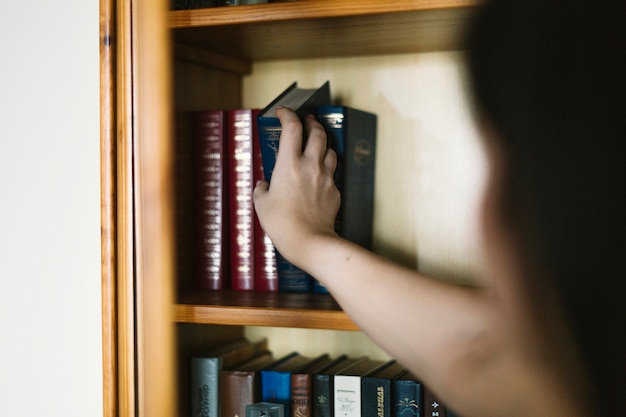 Free Photo crop woman picking old book from shelf