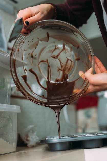 Free photo crop woman pouring batter from mold into tin