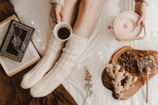 Free photo crop woman pouring tea near books and snacks