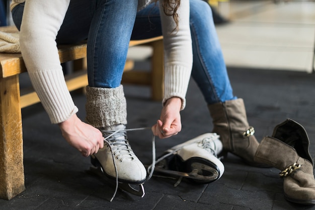 Free photo crop woman putting on ice skates