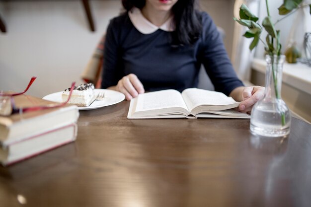 Crop woman reading book in cafe