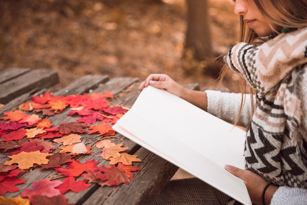 Crop woman reading at table in park