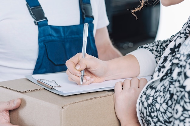 Crop woman signing on clipboard for parcel