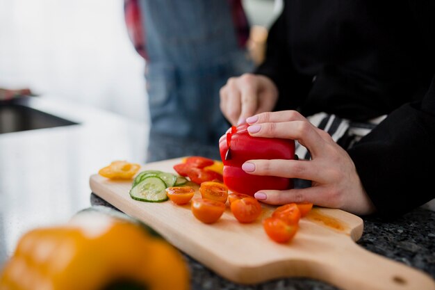 Crop woman slicing pepper for salad