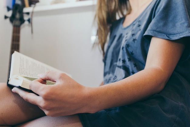 Crop woman in T-shirt reading book