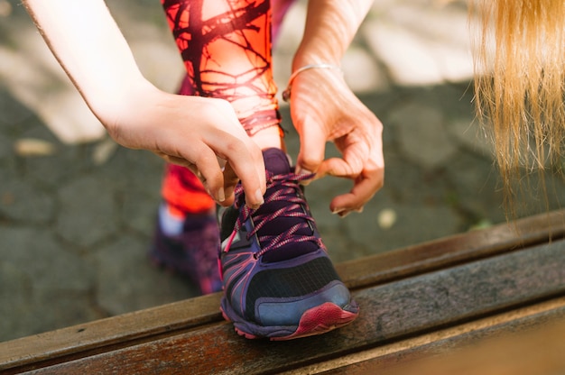 Free photo crop woman tying laces on sneakers