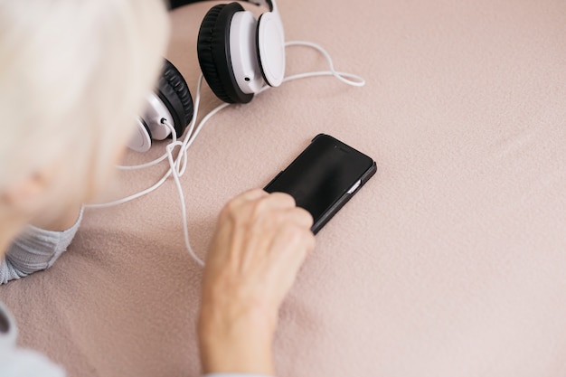 Free photo crop woman using smartphone near headphones