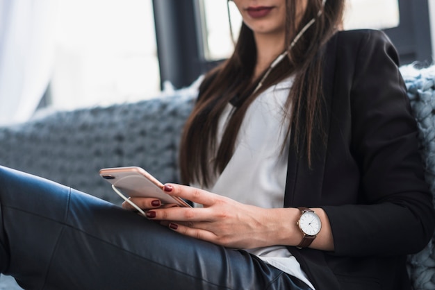 Crop woman using smartphone on sofa