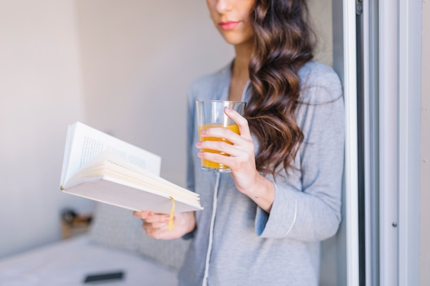 Free photo crop woman with juice reading book