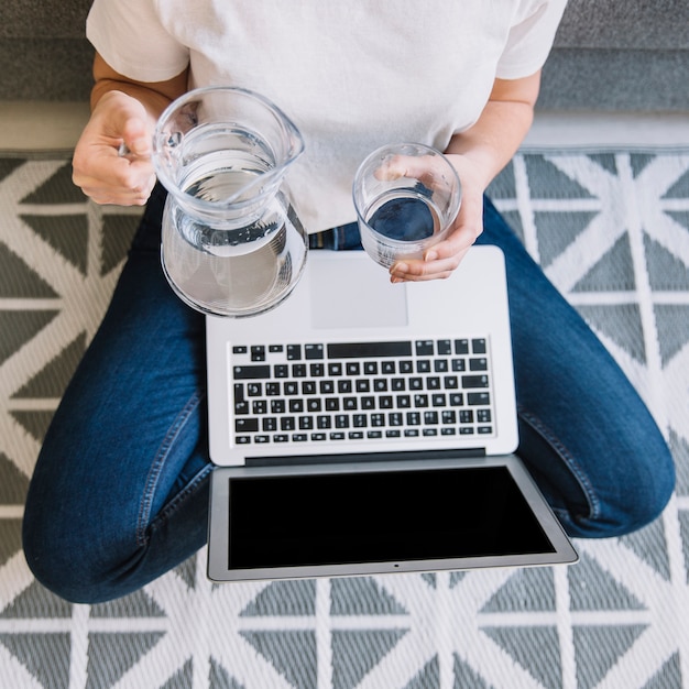 Free photo crop woman with laptop pouring water