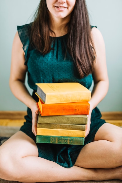 Free photo crop woman with stack of old books