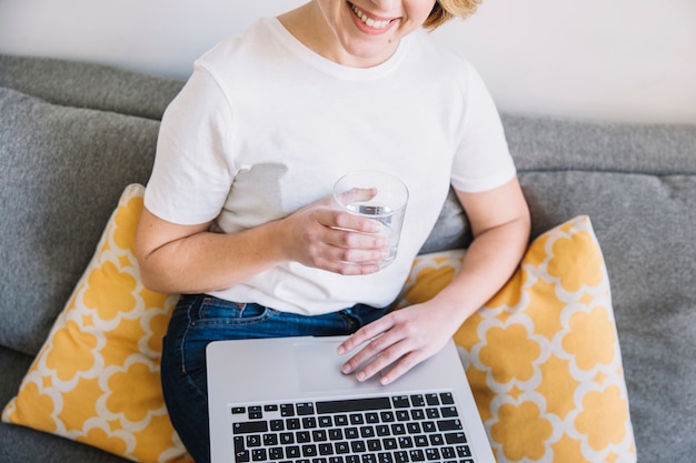 Free Photo crop woman with water browsing laptop