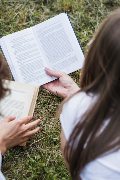 Free photo crop women friends reading books on grass