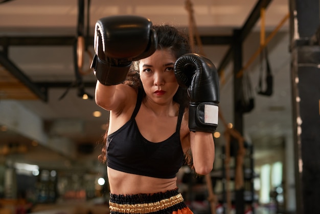 Free photo cropped asian woman training in boxing gloves at muay thai practice