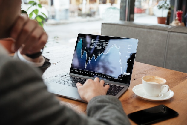 Free photo cropped image of businessman sitting by the table in cafe and analyzing indicators