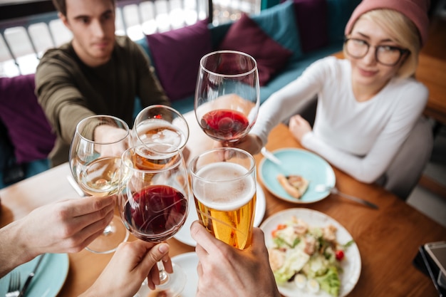 Cropped image of friends sitting in cafe drinking alcohol.