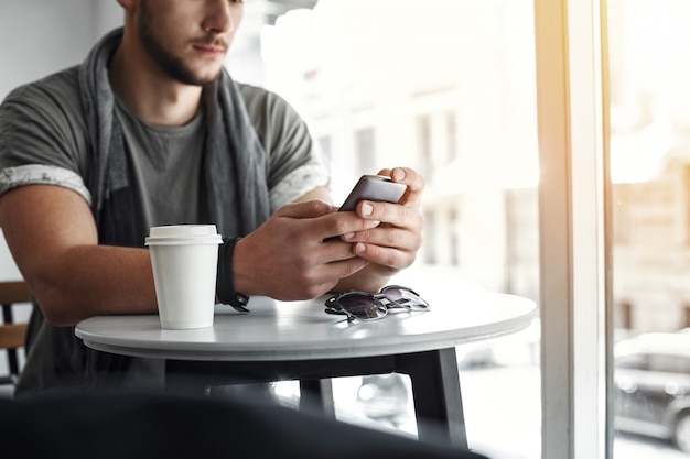 Free Photo cropped image of man texting message on phone at cafe.