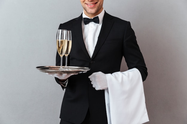 Free photo cropped image of waiter holding glasses of champagne and towel.