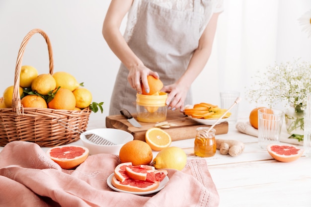 Cropped image of woman squeezes out juice of a citruses.