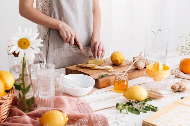 Cropped image of young woman cut the ginger.