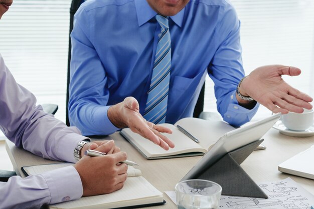 Cropped men discussing annual report using digital tablet