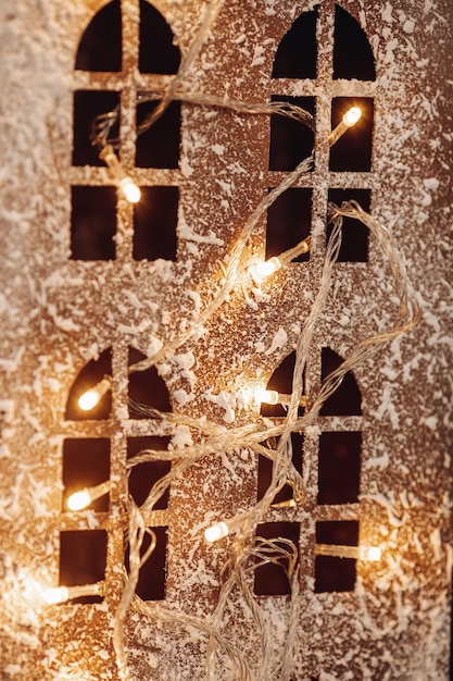 Free photo cropped photo of four windows in cardboard wall decorated with artificial snow and illuminated garland.