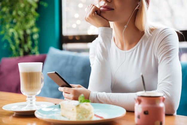 Cropped photo of young lady listening music in cafe.