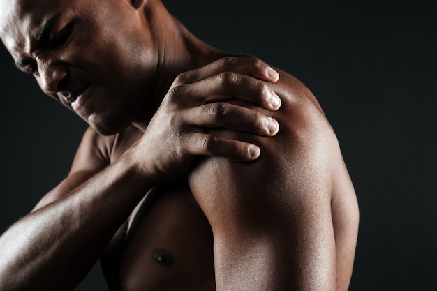 Free photo cropped photo of young shirtless afro american man with shoulder pain