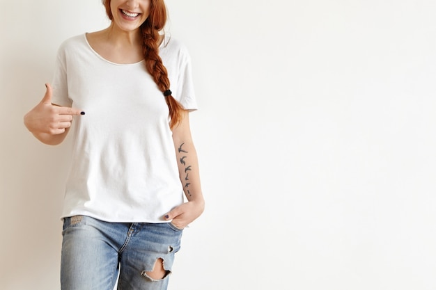 Cropped portrait of attractive redhead European teenager with tattoos