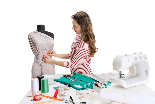 Free photo cropped portrait of young woman sewing dress isolated over white background