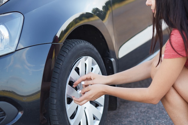 Free Photo cropped shot of brunette female driver going to change flat car tire