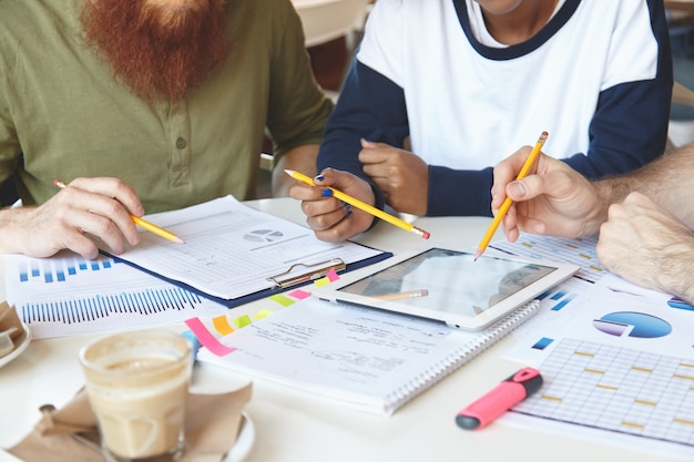 Cropped shot of business colleagues working together and analyzing financial figures on graphs and diagrams.