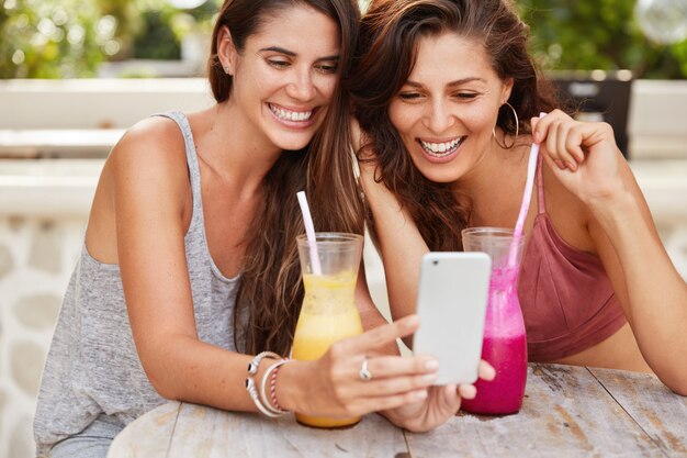 Cropped shot of pleased happy young women do shopping in web stores, glad to choose new purchase