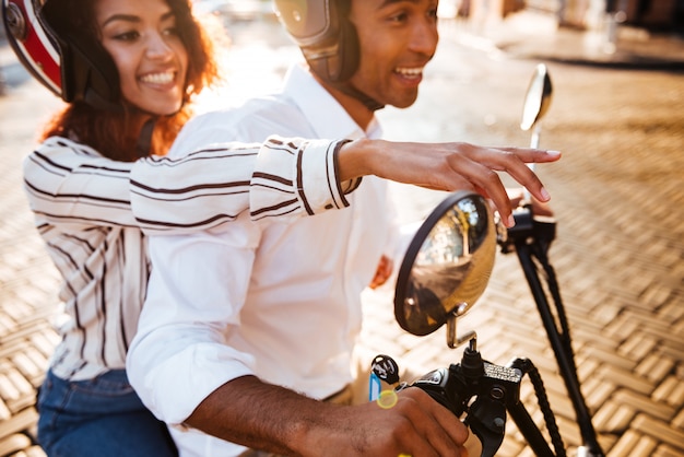 Cropped Side view of pleased african couple rides on modern motorbike on the street