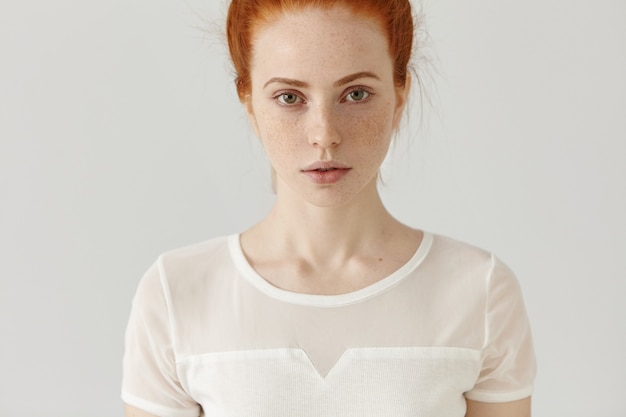 Cropped studio shot of beautiful Caucasian female with red hair and freckles