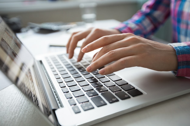 Free photo cropped view of hands typing on laptop