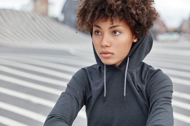 Free photo cropped view of thoughtful dark skinned young sportswoman in stylish hoodie