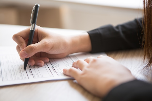 Free photo cropped view of woman filling in application form